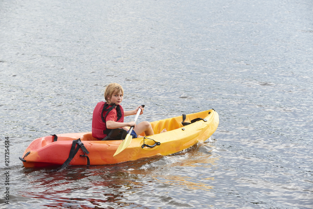 Active happy child. Teenage school boy having fun enjoying adventurous experience kayaking on the lake on a sunny day during summer vacation