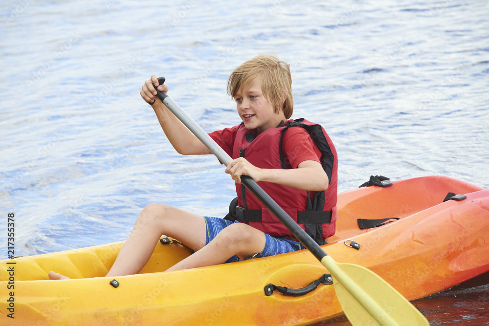 Obraz premium Active happy child. Teenage school boy having fun enjoying adventurous experience kayaking on the lake on a sunny day during summer vacation