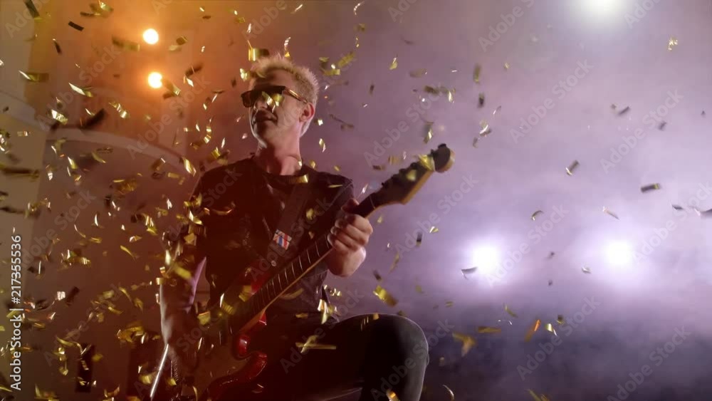 Concert rock band performing on stage with singer guitar. Music video punk, heavy metal or rock group. The guitarist performs on stage. Stage light, smoke. Male playing electric guitar