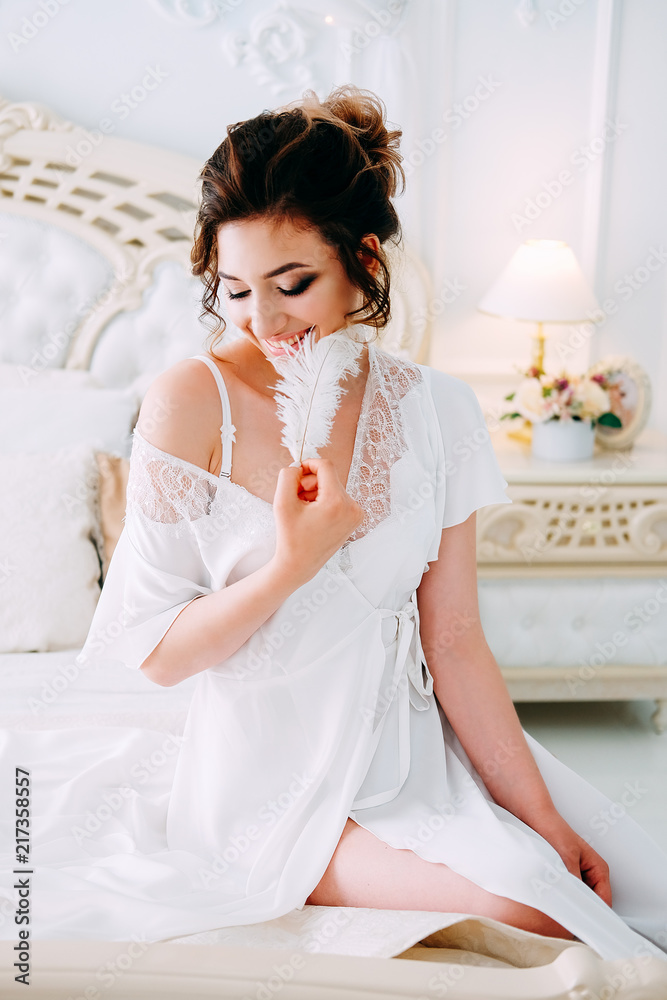 Sensual brunette in silk white robe waiting on the bed Sensual brunette in silk white robe waiting on the bed