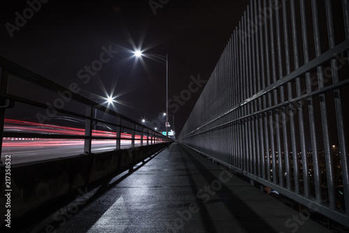The Second Narrows Bridge sidewalk at night, with light trails from passing cars.
