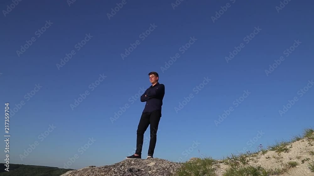 Young attractive man standing othe lands edge and looking far away. Superwide shot. Young attractive man standing othe lands edge and looking far away. Superwide shot.