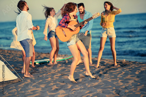 Summer, holidays, vacation, music, happy people concept - young people dancing together at the beach on beautiful summer sunset. © luckybusiness