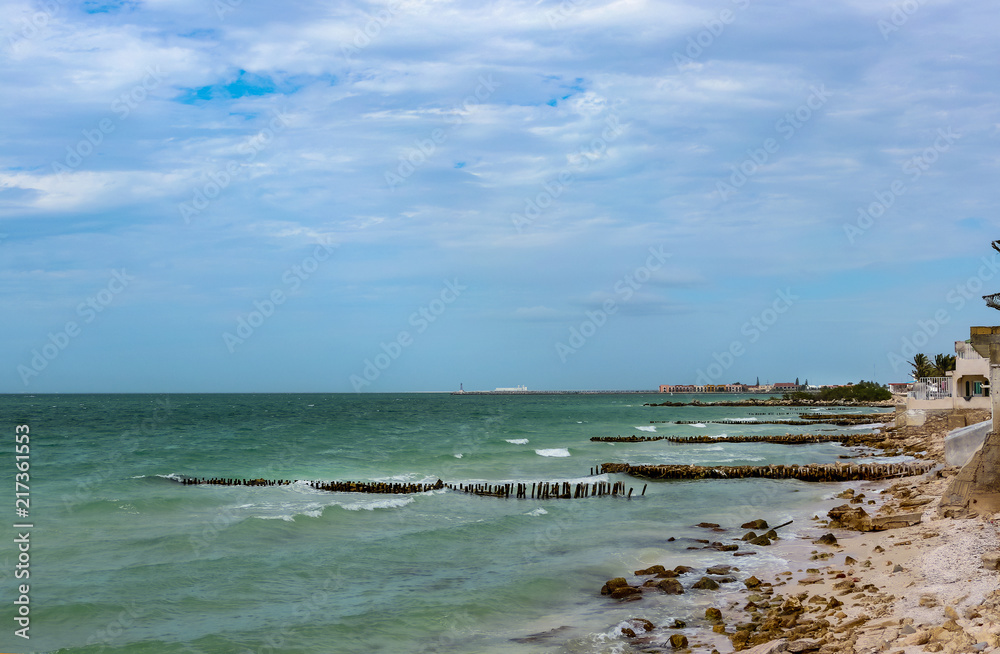 View along eroded beach with sand fencing in Progreso Mexico toward the worlds longest pier that allows ships to dock in the shallow Gulf of Mexico but also causes erosion of the beaches