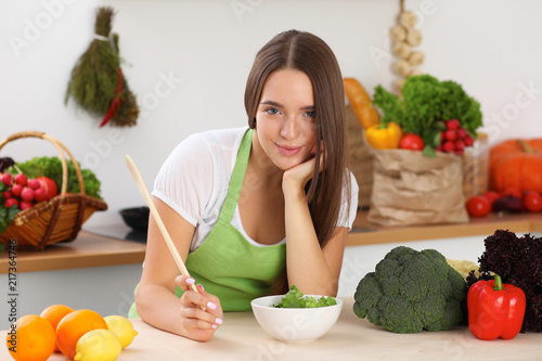 Young woman cooking in kitchen. Householding, tasty food and vegetarian in lifestyle concepts photo