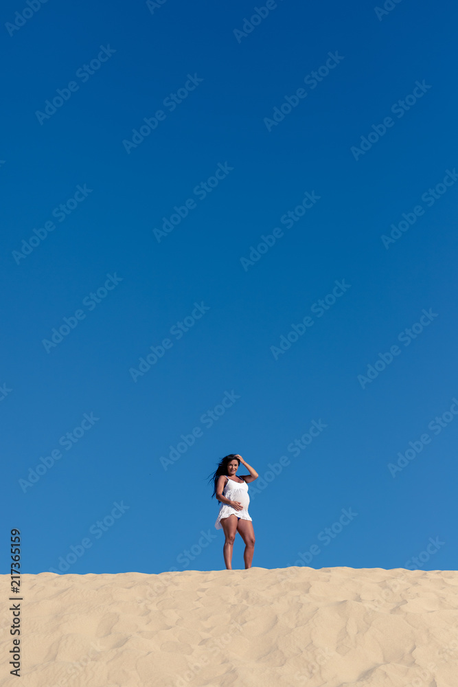 A pregnant model on the beach in summer. 