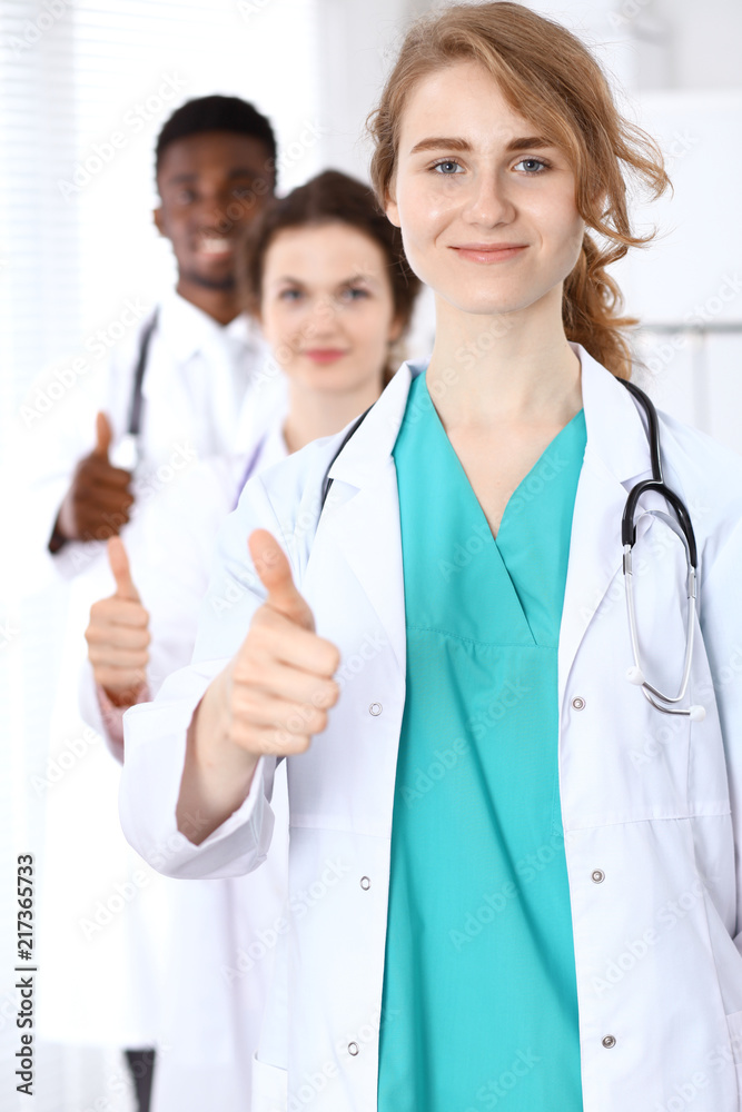 Medical team of confident doctors showing Ok sign with thumbs up. Medicine and health care, insurance concept Medical team of confident doctors showing Ok sign with thumbs up. Medicine and health care, insurance concept