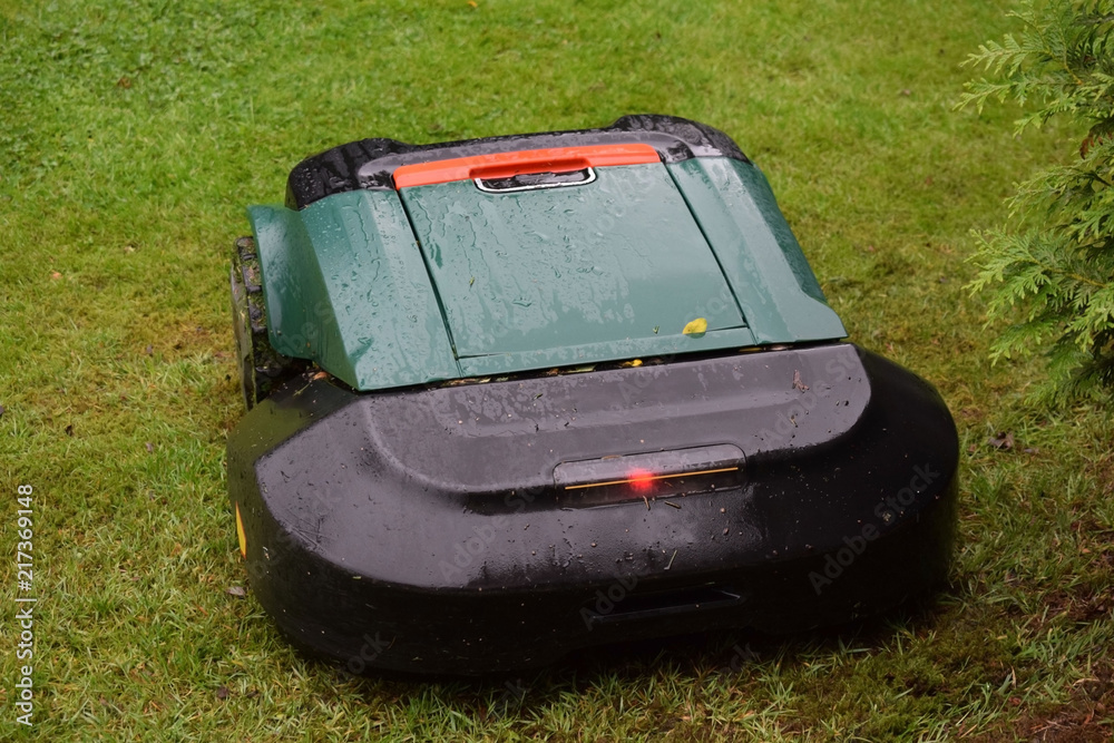 Robot lawnmower in the garden on the slope in the rain. Robot lawnmower in the garden on the slope in the rain.