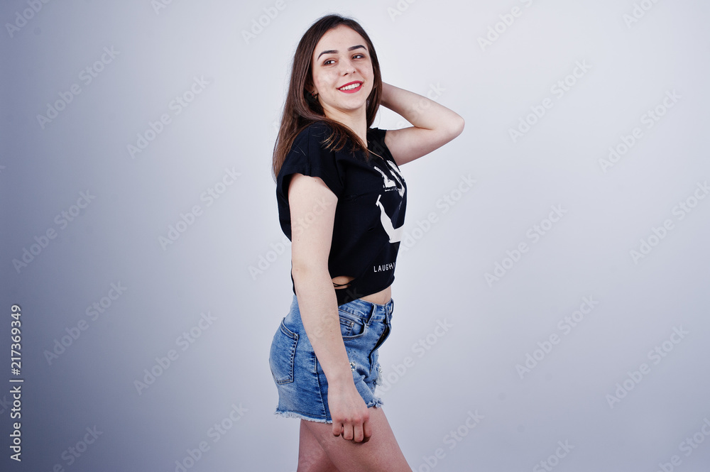 Portrait of an attractive girl in black t-shirt saying lol and denim shorts posing in the studio. Portrait of an attractive girl in black t-shirt saying lol and denim shorts posing in the studio.