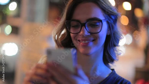 Woman using cellphone at night. Girl starring at smartphone screen in nightlife atmosphere2 photo