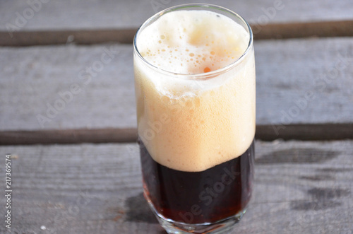 Glass of dark beer on the wooden background