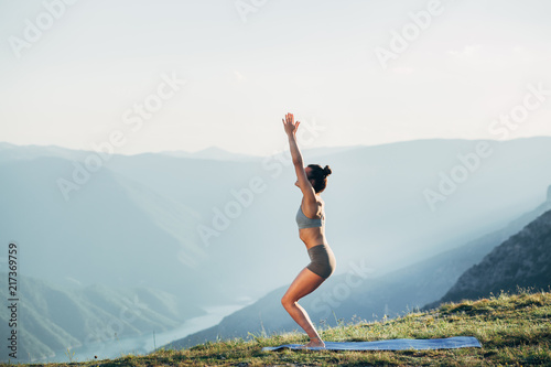 Fit young girl practicing yoga at sunset