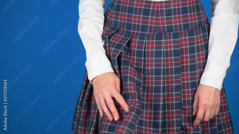 Midsection of teenage girl, cheat sheet written on hips hidden under a skirt. 4k, close-up, blue background, slow-motion shooting.