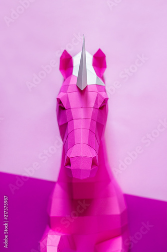 Head of a unicorn of paper on a pink and blue background.