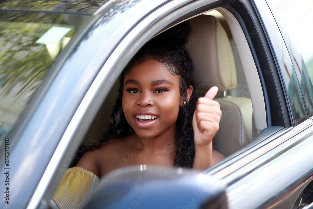 Smiling African American woman in car showing thumb up Smiling African American woman in car showing thumb up