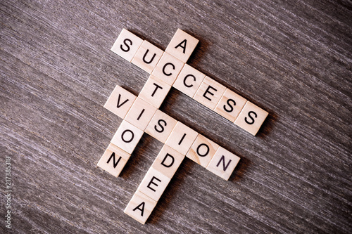 Concept presented by crossword with words idea, vision, action and success with wooden cubes on wooden background