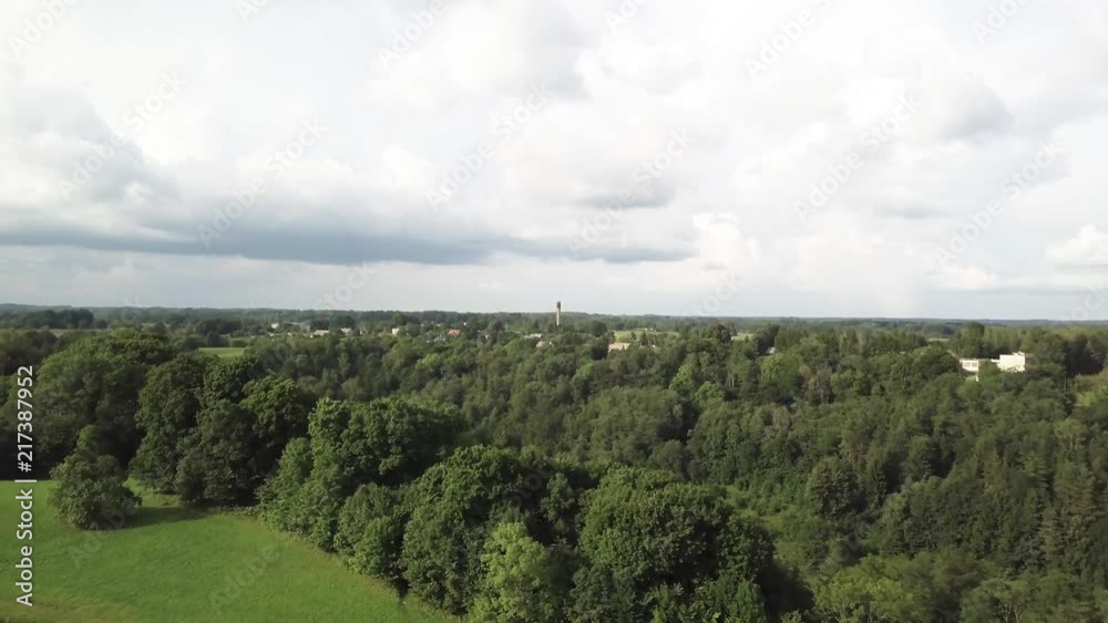 Aerial shot of a tower in a distance surounded by woods Aerial shot of a tower in a distance surounded by woods