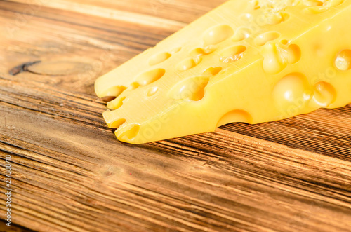 Piece of cheese on wooden table. Selective focus
