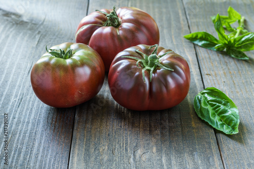 Fresh Black Brandywine Organic Tomatoes and basil on a wooden table. photo