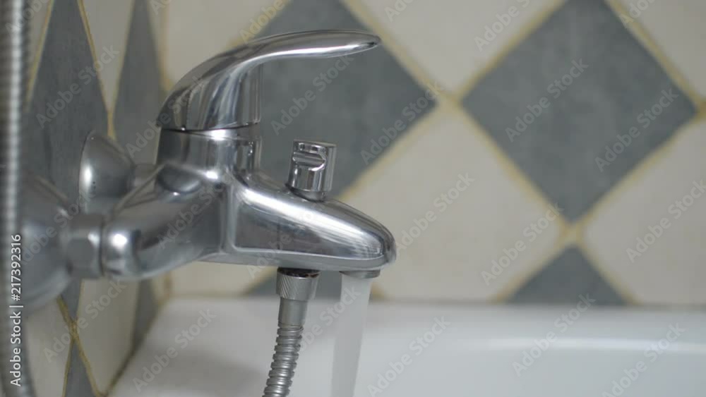 Hand opening a bathtub tap and letting water flow for a while until the hand closes it again. Hand opening a bathtub tap and letting water flow for a while until the hand closes it again.