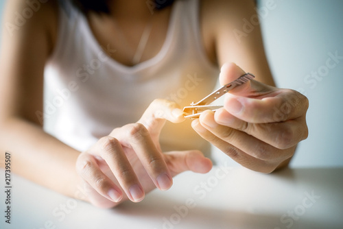 Woman cutting nails with nail clipper Female using tweezers
