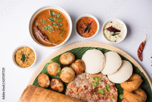 Group of South Indian food like Masala Dosa, Uttapam, Idli/idly, Wada/vada, sambar, appam, semolina halwa, upma served over banana leaf with colourful chutneys, selective focus