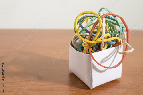 Colored rubber bands in a paper box on a wood table