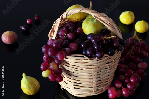 siyah zemin üzerinde sepet içerisinde kırmızı üzüm  ve incirler photo