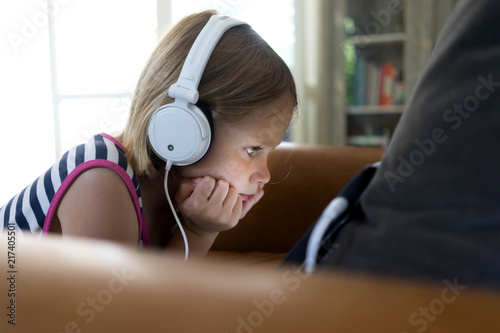 Female child watching her tablet with white head phones on