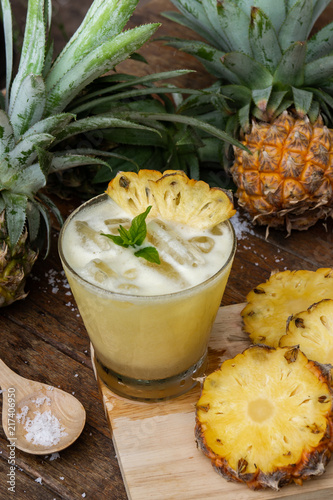 Pineapple juice and pineapple slices cut into pieces on a wooden table. Healthy wood fiber helps to reduce food. Pineapple juice Contains fresh milk, nectar and salt.