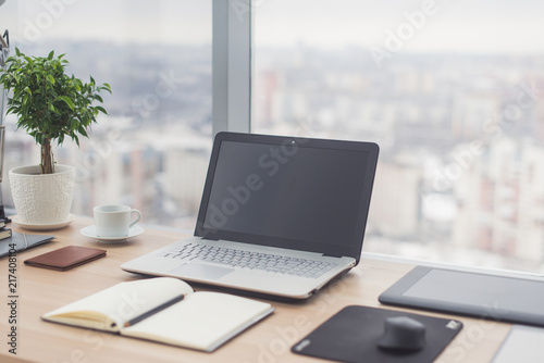 Sideview of office desktop with blank laptop and various tools. © undrey