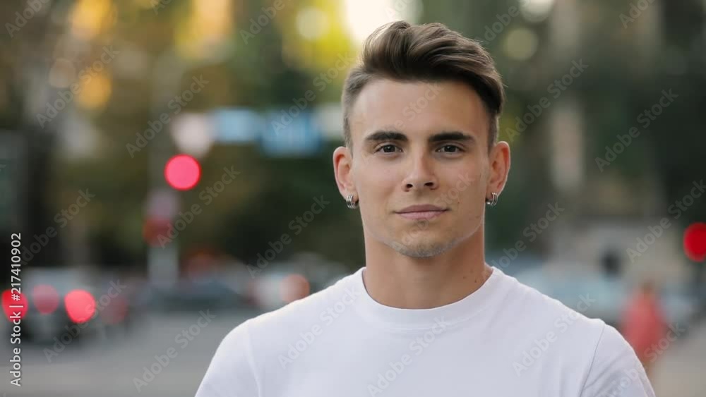 Closeup portrait of young handsome man looking smiling at camera, urban background Closeup portrait of young handsome man looking smiling at camera, urban background