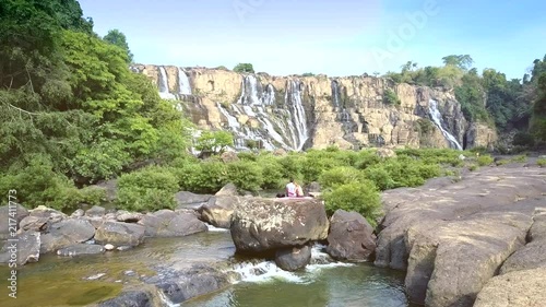 distant view man woman sit on rock among landscape photo