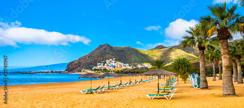 Amazing view of beach las Teresitas with yellow sand, umbrellas, longues and palm trees. Location: Santa Cruz de Tenerife, Tenerife, Canary Islands. Panorama photo