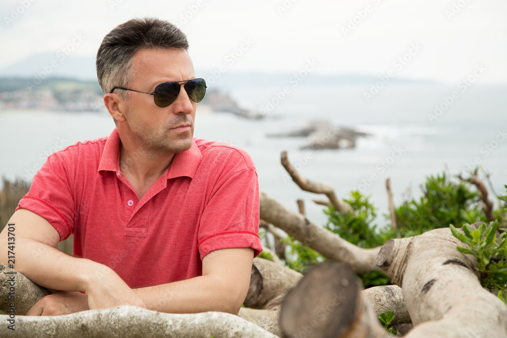 Handsome middle-aged man posing at the beach. Attractive mid adult male model posing at seaside.  Outdoor portrait of beautiful man, image toned.