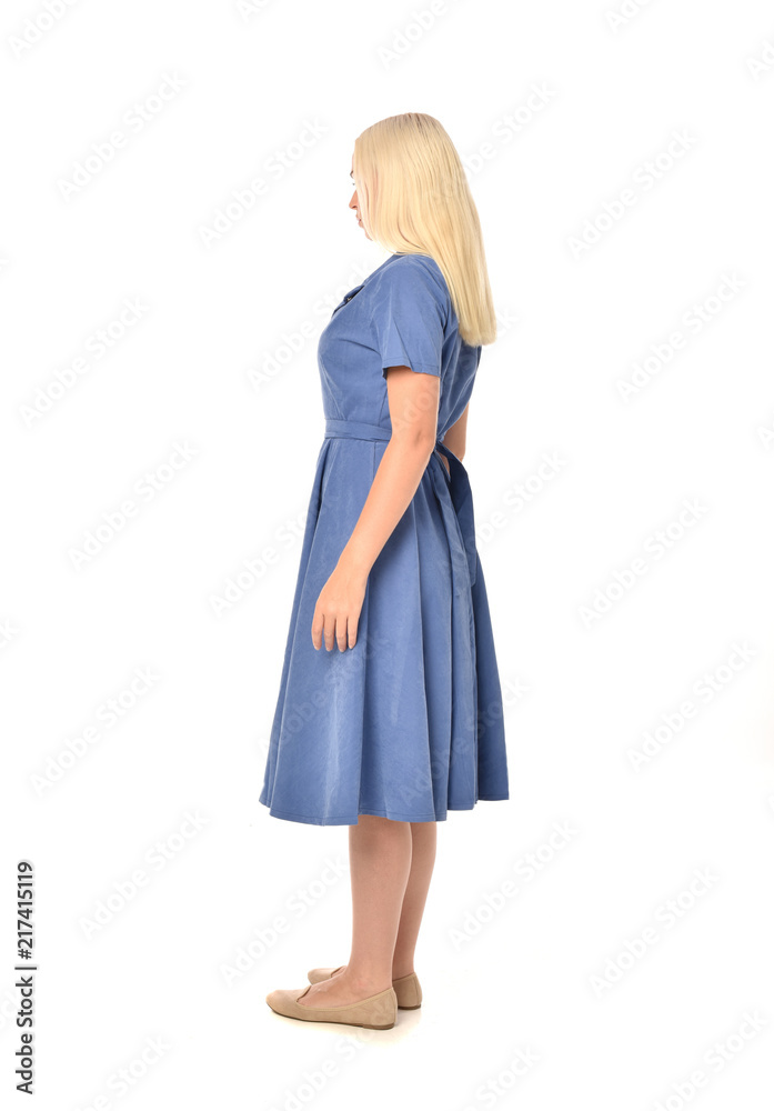 full length portrait of blonde girl wearing blue dress. standing pose with back to the camera. isolated on white  studio background.