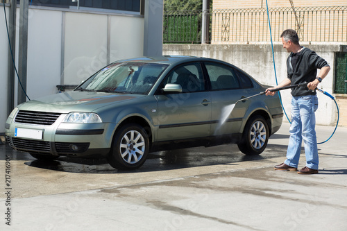 Car washing. Man cleaning car using high pressure water and brush outdoor © Khorzhevska