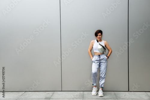 Young attractive woman posing outdoor over silver metal background wall. Beautiful girl. Beautiful caucasian model's portrait.