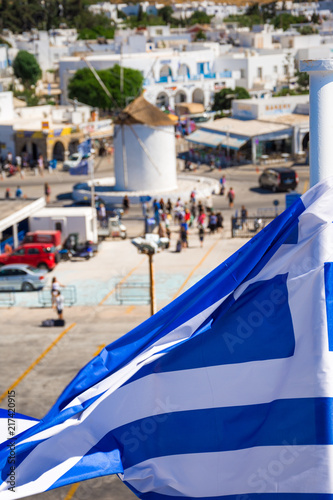 Greek flag over Paros harbor with wind mill, Cyclades, Greece. Theme of Cyclades, Greece.