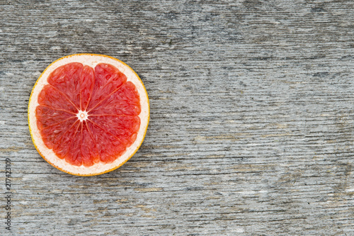 Pink ripe grapefruit slice on old wooden background
