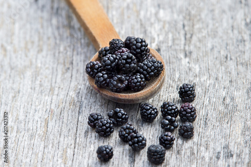 Ripe blackberries in wooden spoon on old wooden background