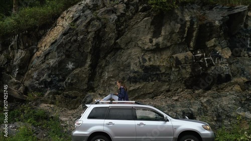 Female freelnacer is working with laptop on the roof of her car photo