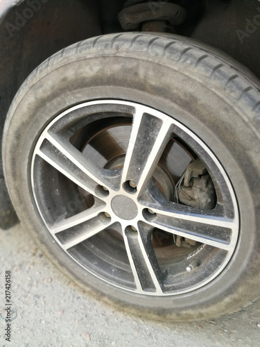 The dusty wheel of a car with a cast disk.