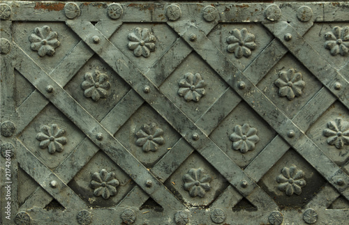 Ancient forged metal texture with decorative overlays. Doors, gates, shutters. Detail of a medieval gray door with metal decoration, background, close-up.