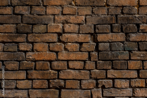 Old brown brick exterior wall with dark spots