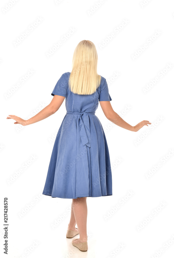 full length portrait of blonde girl wearing blue dress. standing pose with back to the camera. isolated on white studio background. full length portrait of blonde girl wearing blue dress. standing pose with back to the camera. isolated on white studio background.