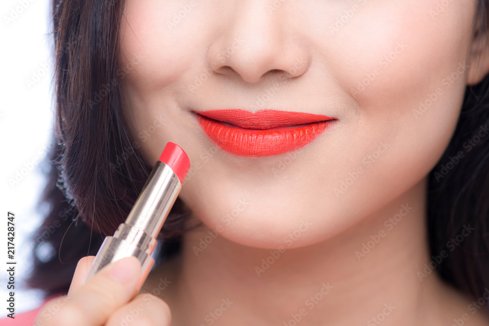 Pretty asian young woman applying red matt lipstick on her lips