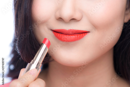 Pretty asian young woman applying red matt lipstick on her lips © makistock