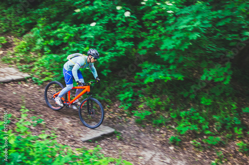 A cyclist in a helmet is riding off-road, motion blur