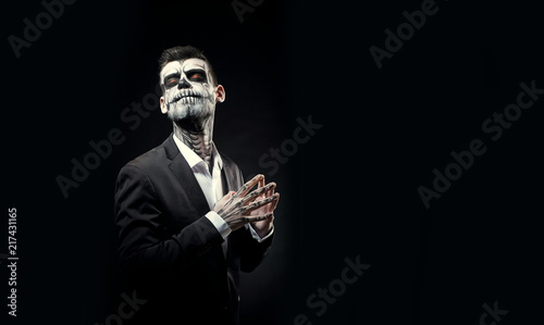 Portrait of man with Halloween skull makeup on the black background.